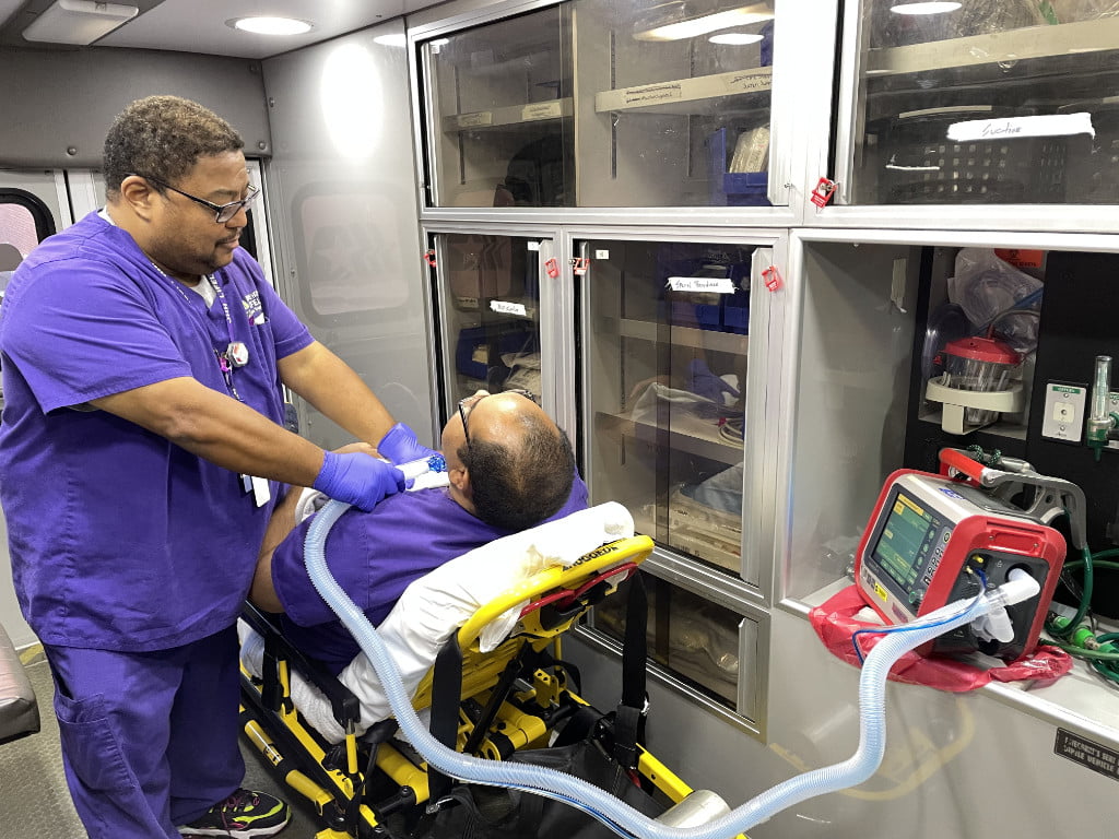 A medical provider helps a patient on a vent.