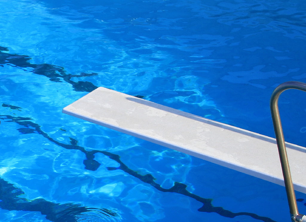 A diving board over a blue-colored pool.