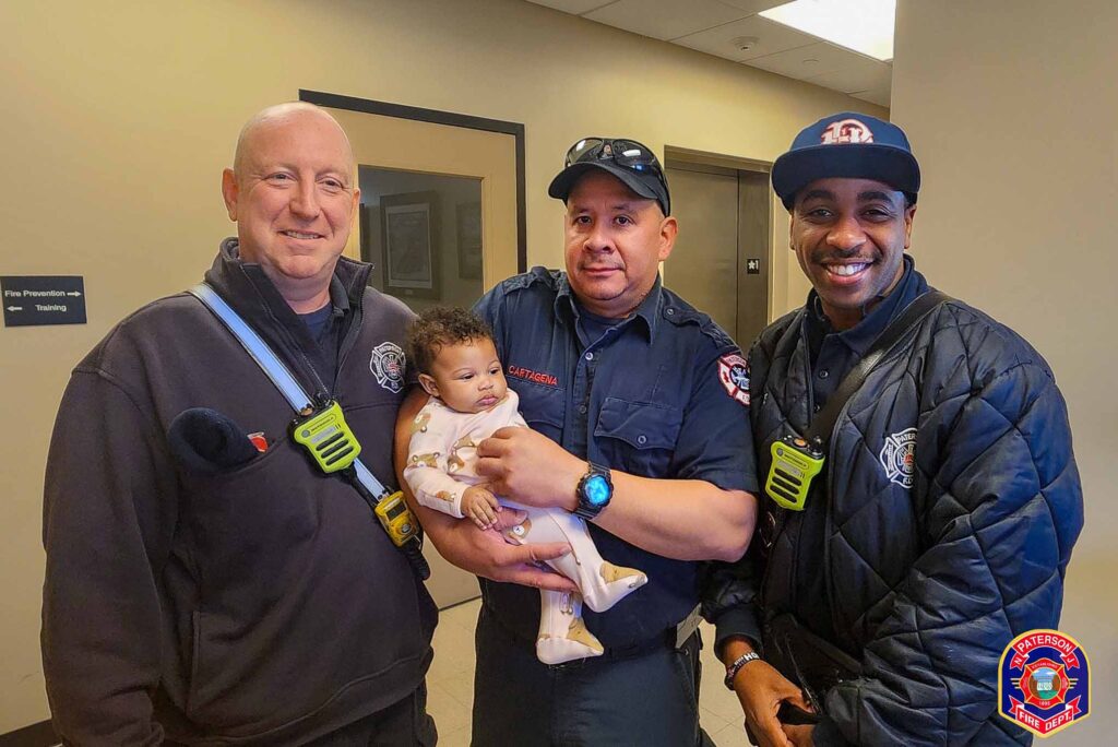 Three men pose for a picture while one of the men hold a baby.